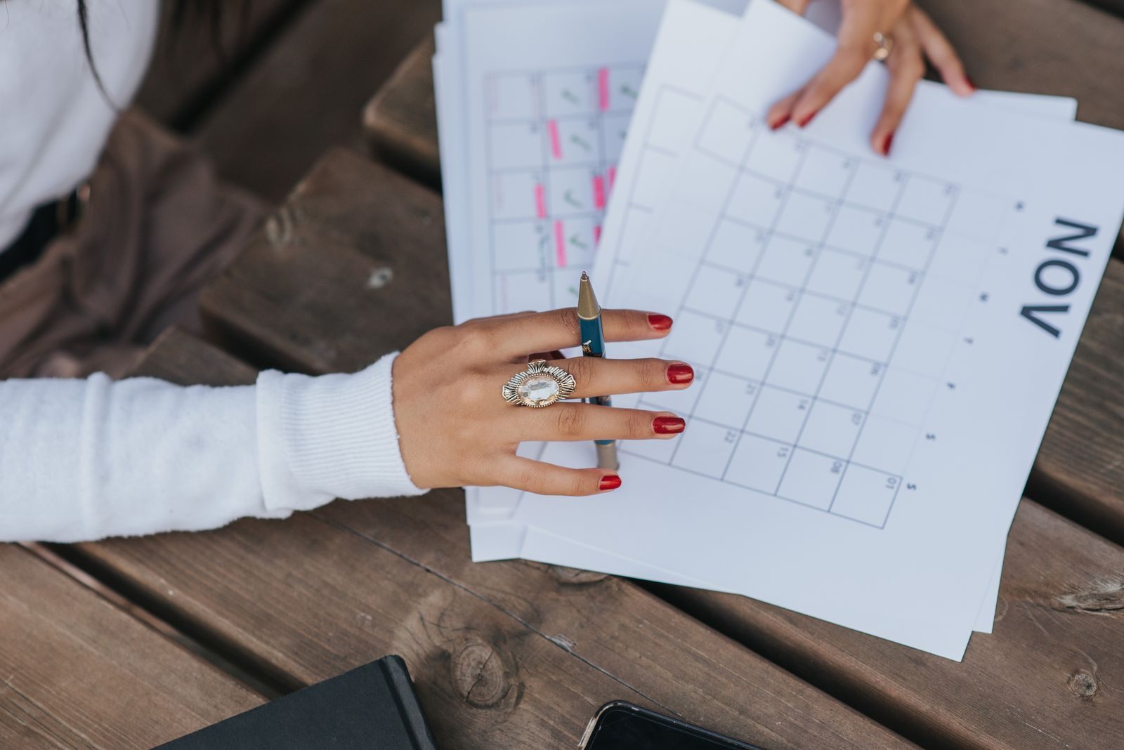 A woman holding printed monthly calendar pages, planning which cruise fare types fit her dates