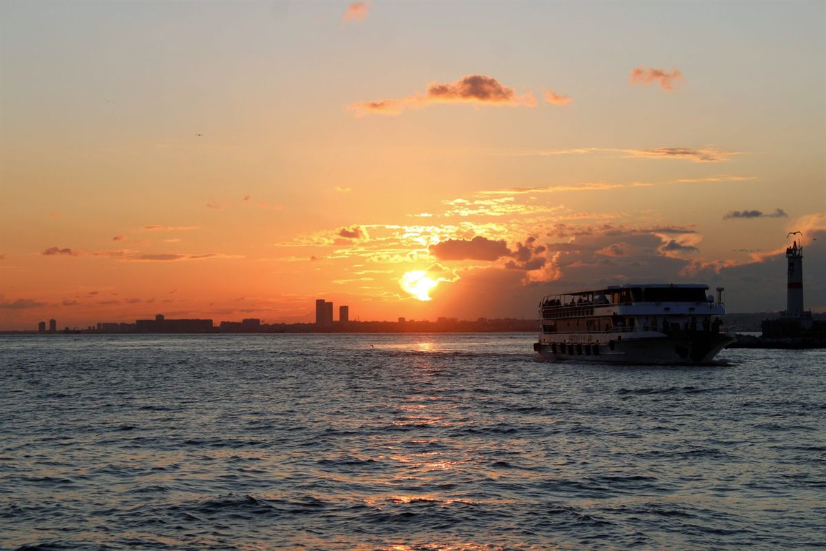 A passenger ferry passing a lighthouse at sunset