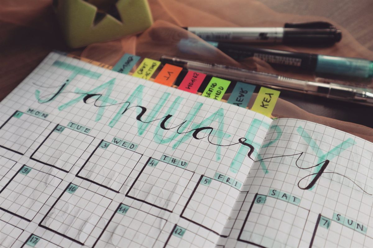 A handwritten January planner page with coloured tabs and pens